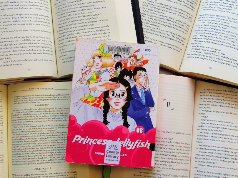 Picture of princess jellyfish volume 8 against open book pages.